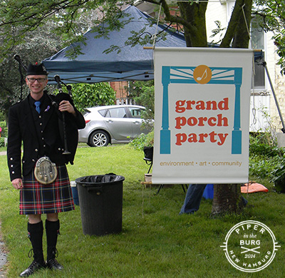 Bagpiper standing next to banner hanging from tree that reads "Grad Porch Party"
